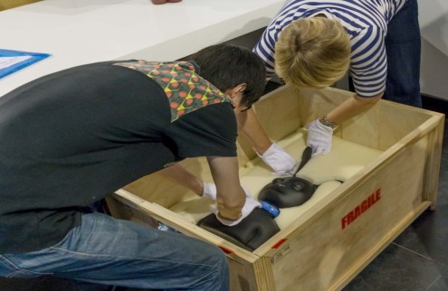 Two people help pack artwork into a crate after an exhibition