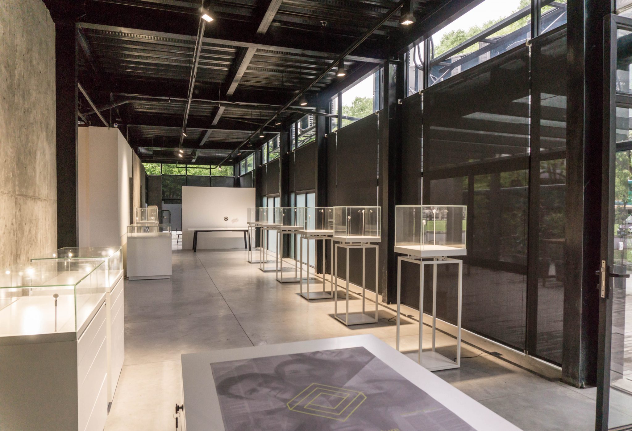 A photograph of an large open room, with glass boxes atop of plinths sitting along the walls