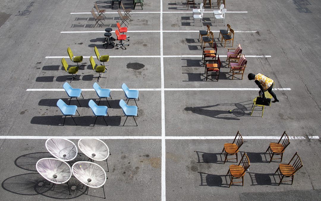 39 chairs arranged in car parking spaces with person standing on one.