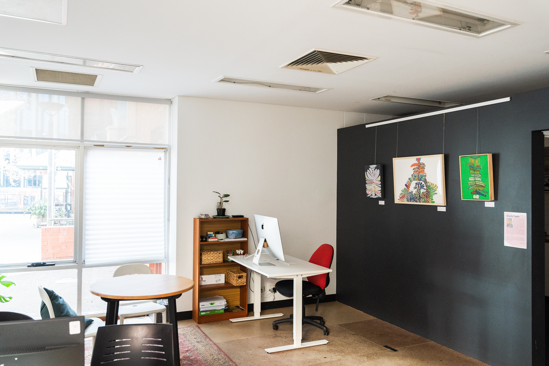 A photograph of the Guildhouse office space, with plants in the left and right side of the image, with a dark artwork in the centre