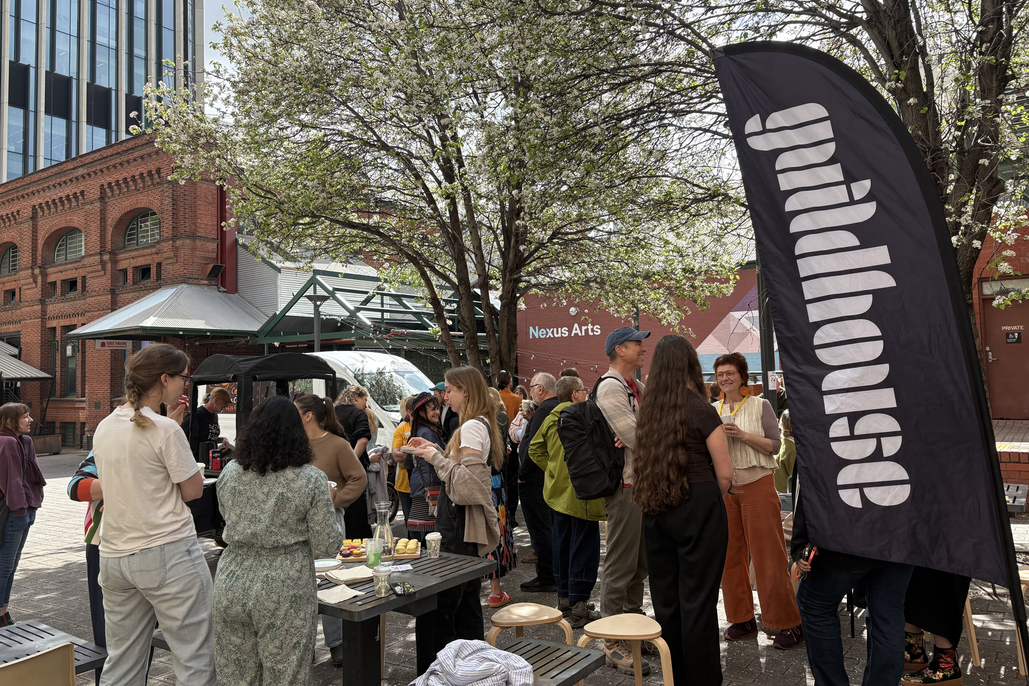 A photograph of a a cafe with laptops and coffee. In the background is a shelving unit with various items including speakers